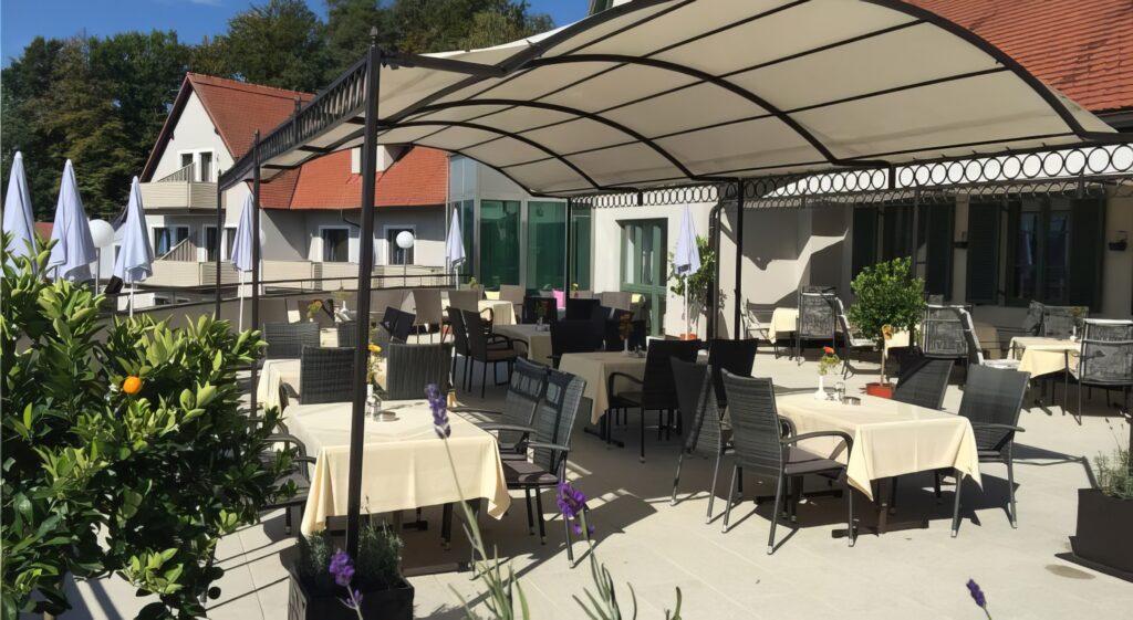 Gemütliche Terrasse eines Restaurants mit Tischen und Stühlen